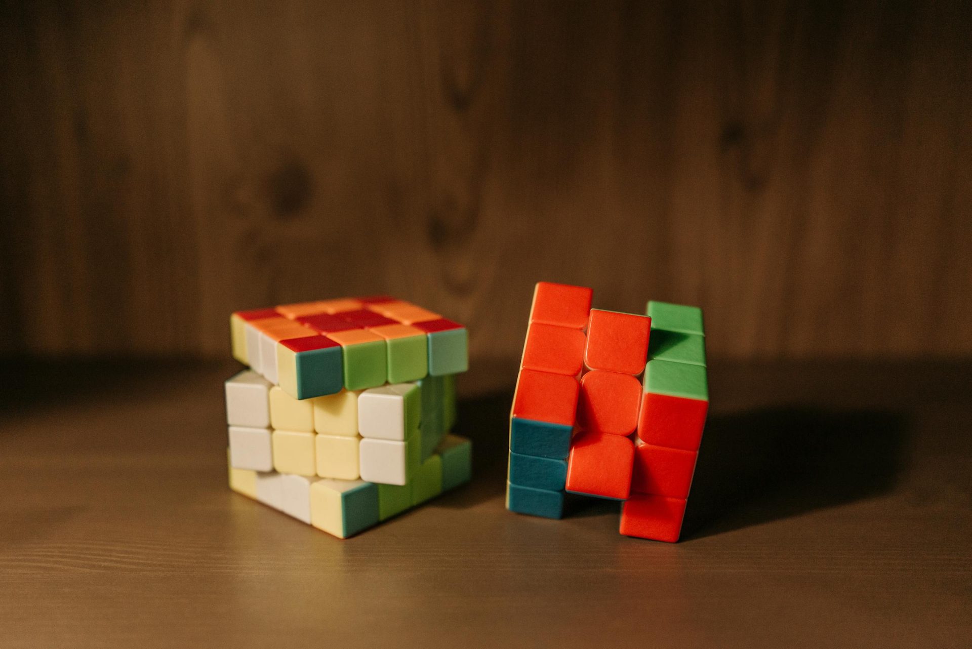 2 Rubiks Cube posés sur une table en bois marron foncé