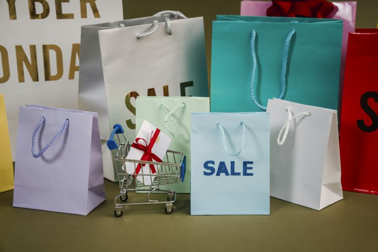 Petit caddie entouré des sacs pleins d’achats en soldes